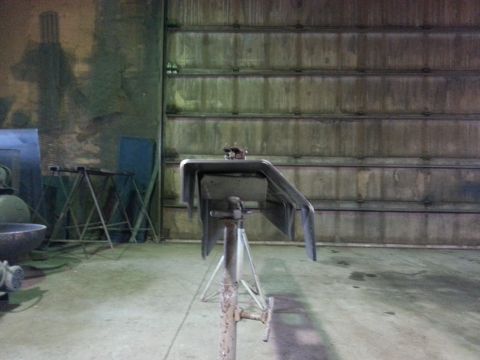 1994 Ford Bronco - A vehicle part is mounted on a stand in a workshop setting, with a large corrugated metal door in the background.