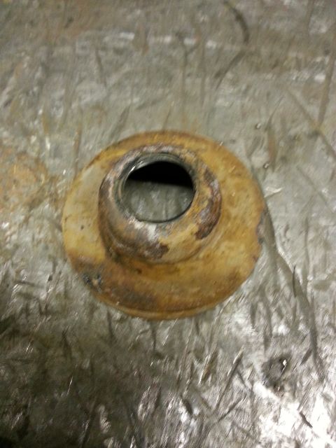 1994 Ford Bronco - A close-up view of a rusty metal component with a central hole, possibly a suspension part.