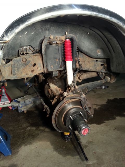 1994 Ford Bronco - Front suspension and wheel assembly of a vehicle undergoing maintenance, showing the brake rotor and hub.