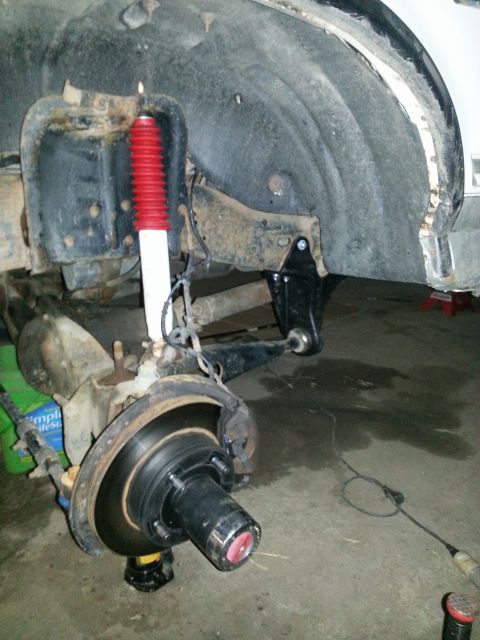 1994 Ford Bronco - The front suspension and wheel assembly of a vehicle is shown, with visible rust on the upper body panel.