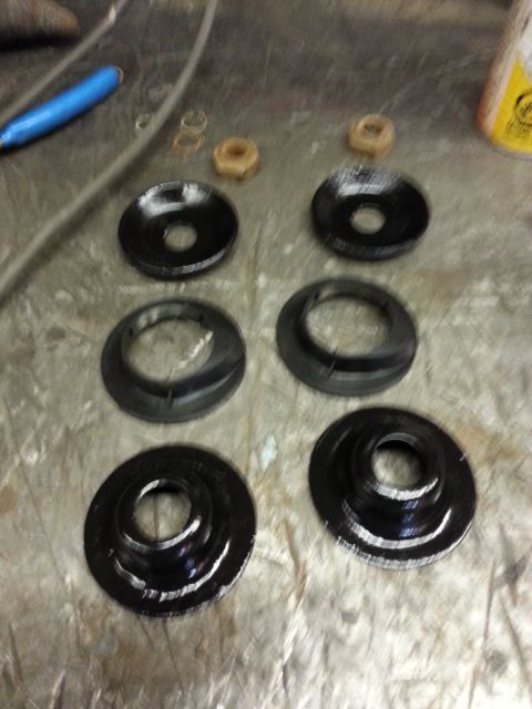1994 Ford Bronco - Several black spring isolators and a few nuts are laid out on a metal surface.