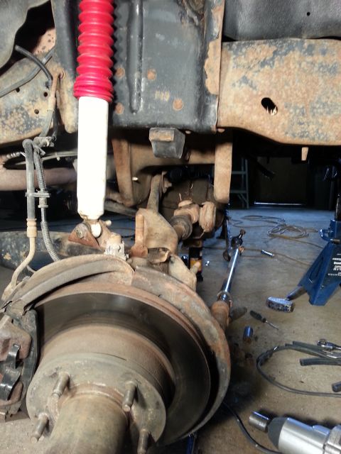 1994 Ford Bronco - Close-up of a vehicle's front suspension and brake components during a repair.