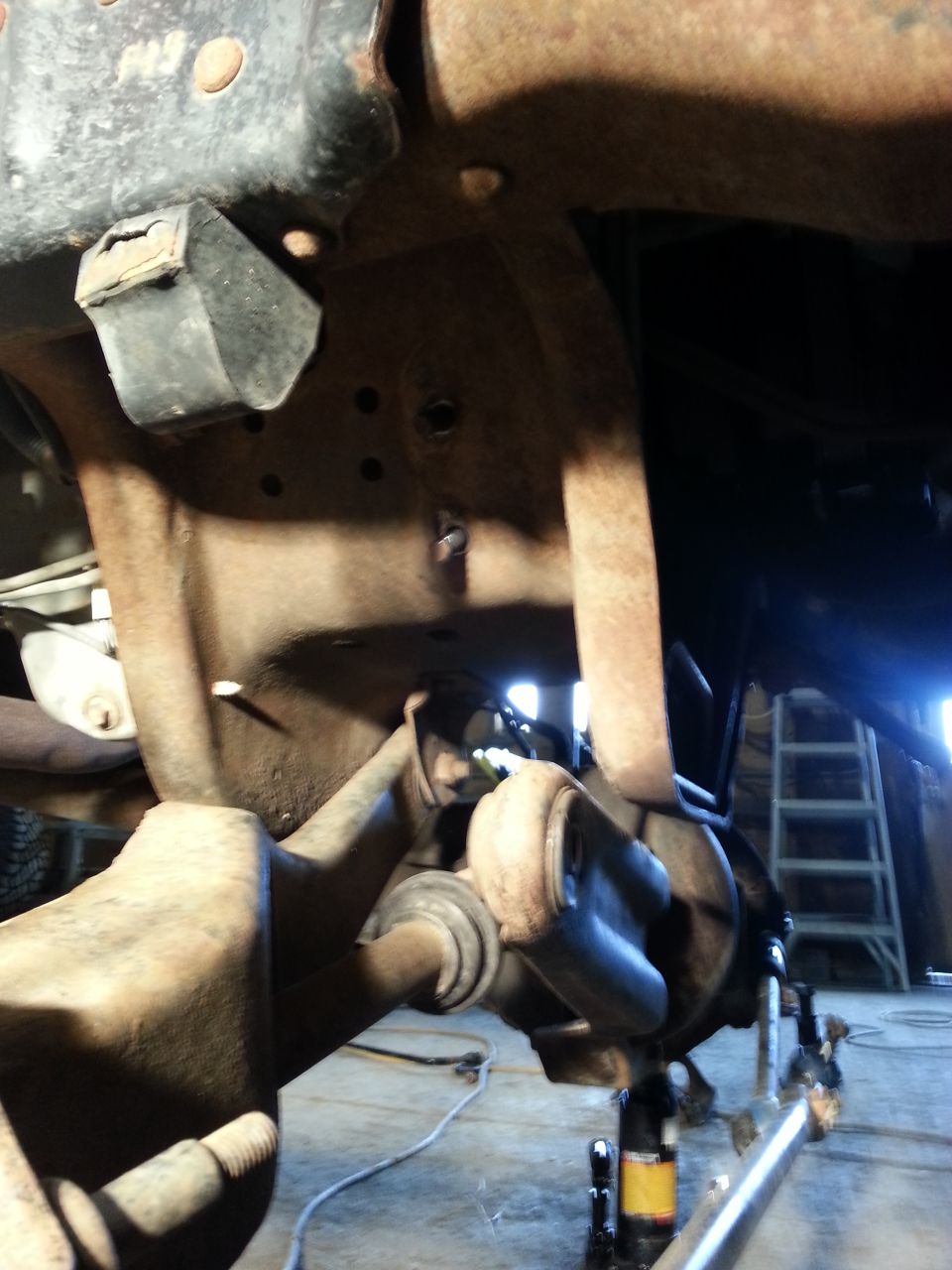 close-up of rusty vehicle frame and suspension parts, possibly under repair
