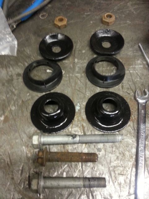 1994 Ford Bronco - Automotive suspension parts laid out on a workbench, including bolts, nuts, and spring isolators.