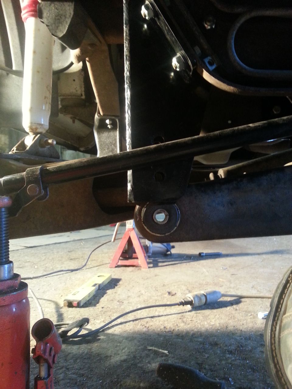 Close-up of vehicle suspension and frame with jack stands and a floor jack