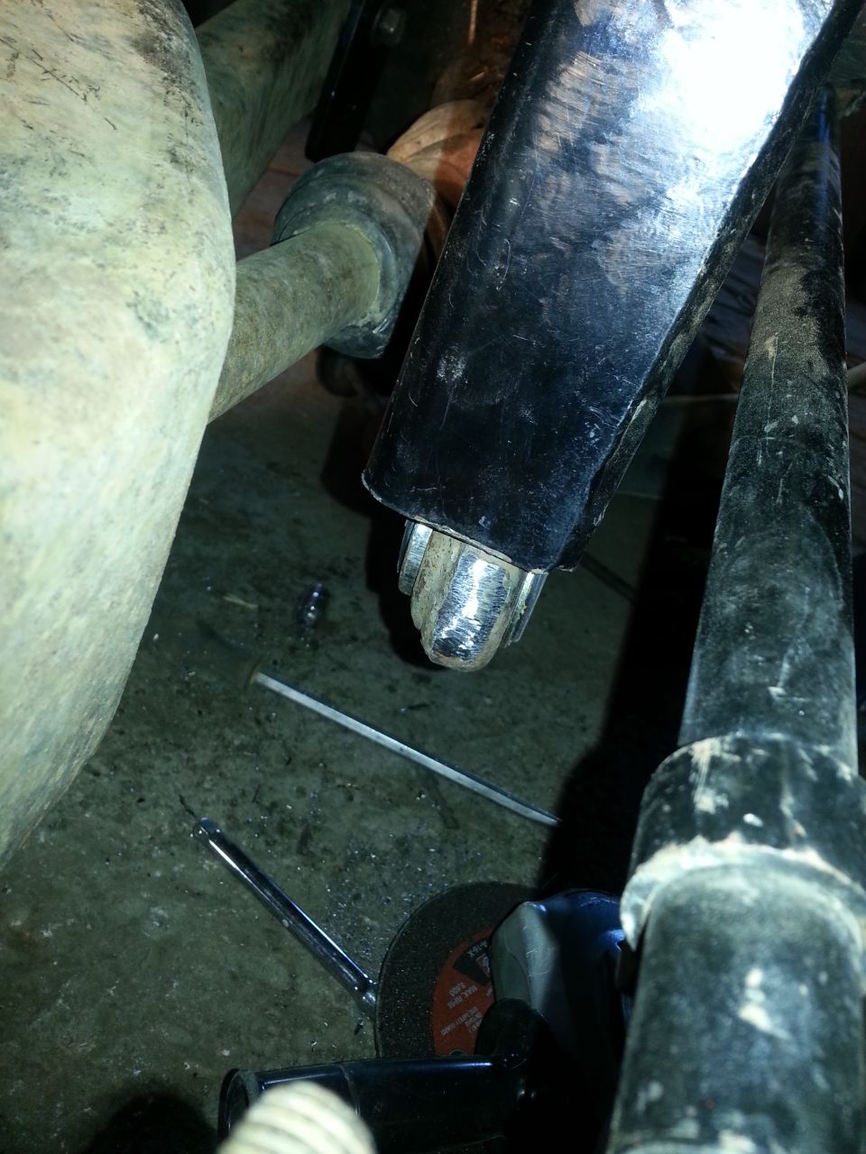 Close-up of vehicle suspension parts with a cutting tool nearby