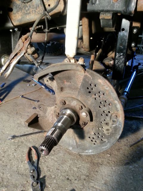 1994 Ford Bronco - Close-up of a vehicle's front wheel hub and brake rotor assembly, with various tools present.
