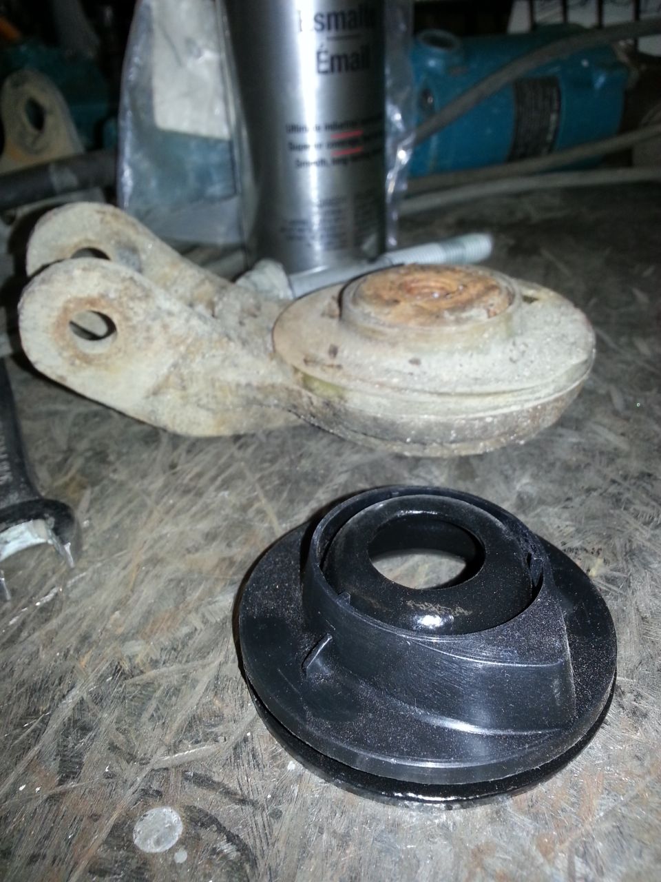 rusty metal suspension component and a black rubber part on a workbench