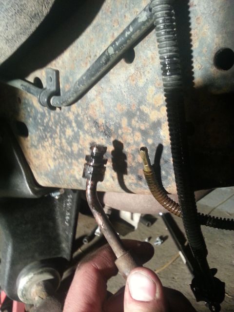 1994 Ford Bronco - Brake line disconnected from vehicle frame, showing rusty metal and hoses.