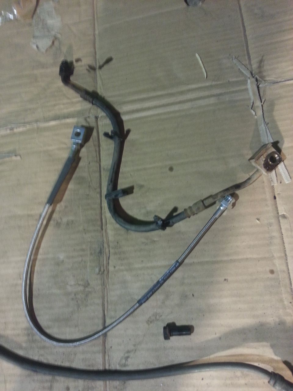 brake hoses and a bolt on a cardboard surface
