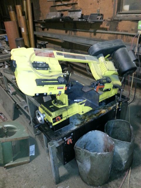 1994 Ford Bronco - A yellow and black band saw is set up on a workbench in a cluttered workshop environment.