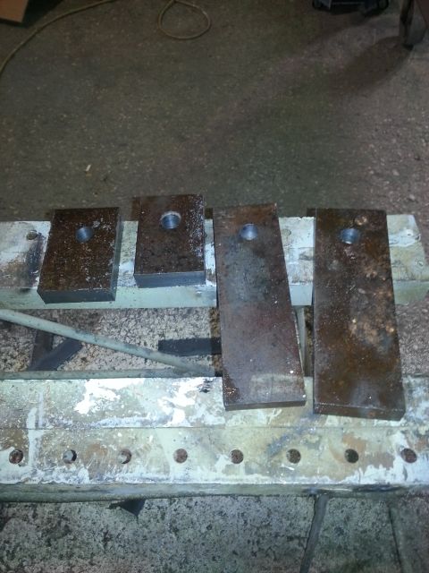 1994 Ford Bronco - Four metal blocks, each with a central hole, are laid out on a workbench.