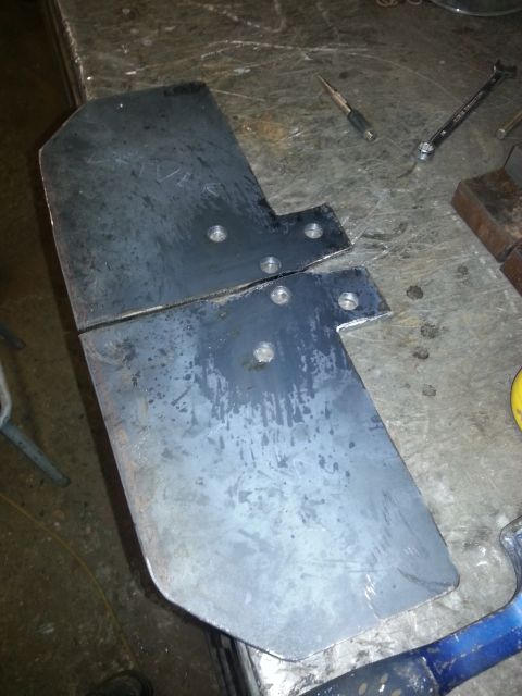 1994 Ford Bronco - Two metal plates with pre-drilled holes sit on a workbench next to tools.
