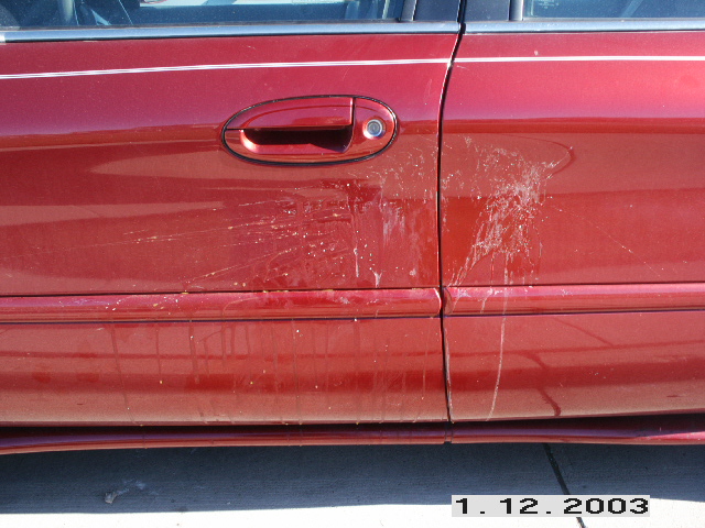 Red 1998 Mercury Sable door with bird droppings and a pinstripe