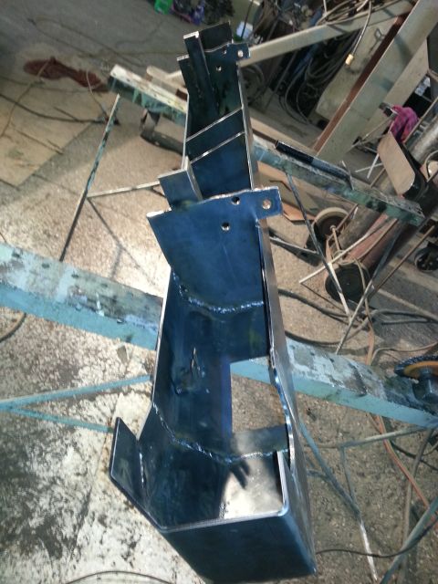 1994 Ford Bronco - Custom welded metal bracket sits on a workbench in a workshop.