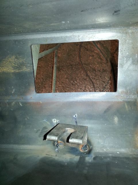 1994 Ford Bronco - A metal bracket is welded onto the vehicle's frame, near an opening that shows insulation and wiring.