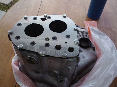 1995 Ford Probe - This is a metal automotive transmission housing with multiple bolts and two large circular openings.