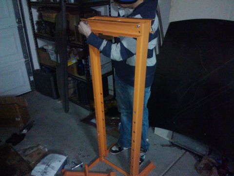 1995 Ford Probe - Person assembling an orange engine hoist frame in a garage setting.