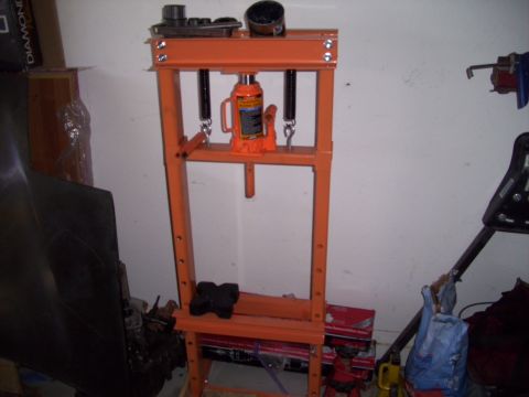 1995 Ford Probe - A hydraulic press is shown in a garage, with various tools and parts in the background.