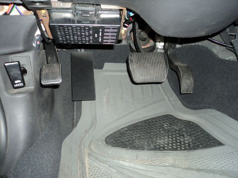 2004 Mercury Grand Marquis - Footwell view of a 2004 Mercury Grand Marquis, showing the brake, accelerator, and clutch pedals, along with the fuse box and hood release.