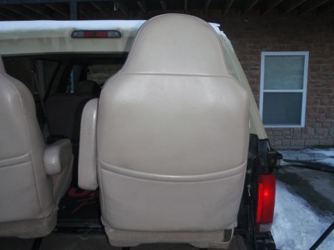 1994 Ford Bronco - Interior view of tan captain's chairs inside a vehicle, with a brick wall and window in the background.