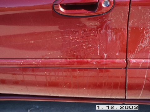 1998 Mercury Sable - Close-up of a red car door showing damage and debris.