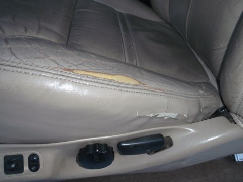 1994 Ford Bronco - Interior shot of a damaged leather car seat with visible wear and tear.