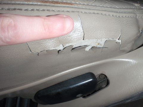 1994 Ford Bronco - Close-up of a damaged tan car seat interior, showing significant wear and tear on the upholstery.