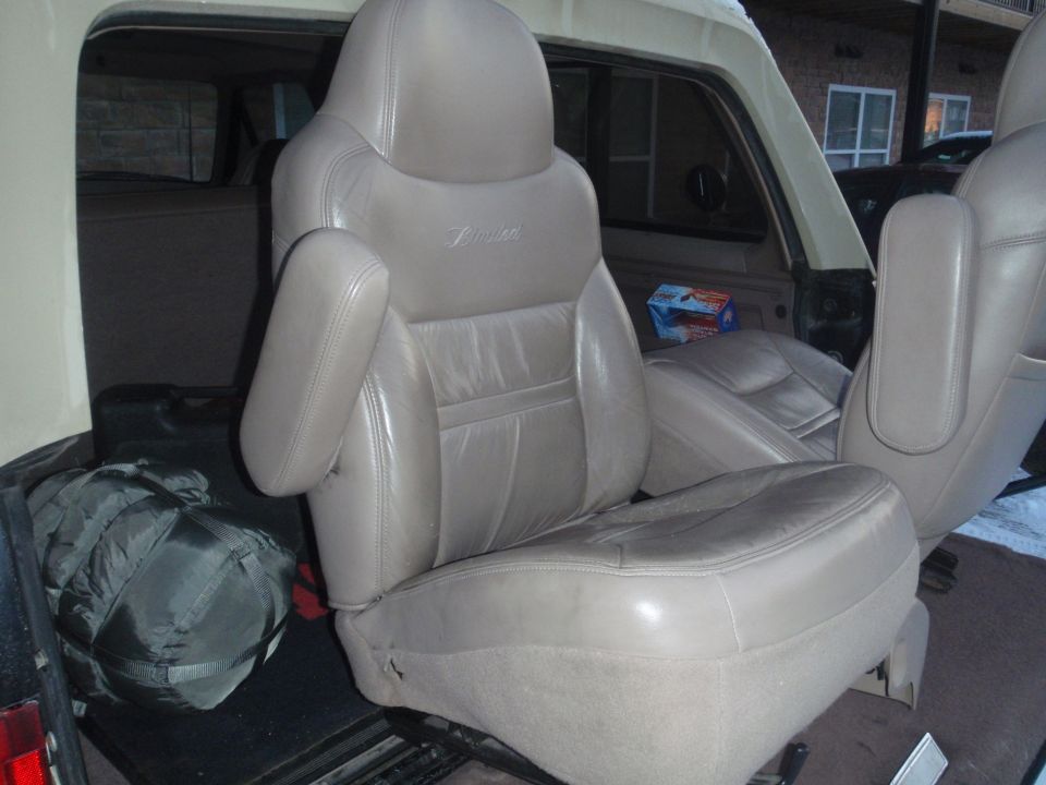 1994 Ford Bronco interior showing tan leather front seats and a sleeping bag in the cargo area