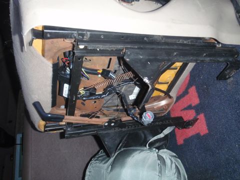 1994 Ford Bronco - Exposed wiring and mechanisms beneath a vehicle seat are visible in this close-up shot.