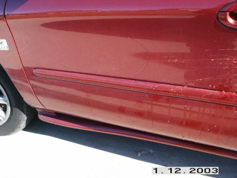 1998 Mercury Sable - Side view of a red 1998 Mercury Sable, highlighting the door trim and visible scratches on the rear quarter panel.