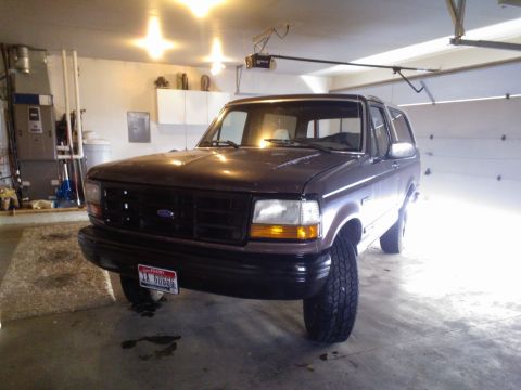 1992 Ford Bronco - A 1992 Ford Bronco is parked inside a garage, showing its front end and side profile.