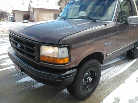 1992 Ford Bronco - The front quarter view of a brown 1992 Ford Bronco shows its distinctive grille and bumper design.