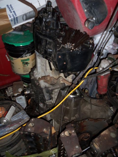 1989 Ford Bronco - Various automotive parts, including a transmission and engine components, are stored together with a green bucket and yellow wire.