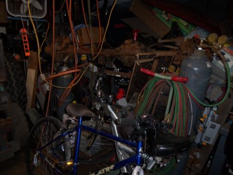 1989 Ford Bronco - A messy garage scene with bicycles, welding equipment, and various stored items.