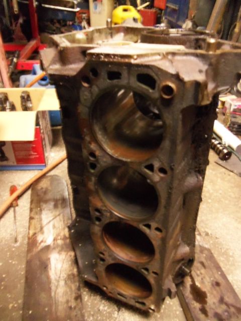 1989 Ford Bronco - A rusty engine block sits on wooden planks in a workshop environment.