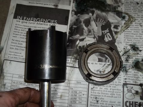 1990 Ford Bronco - A black socket wrench part and a bearing are placed on a newspaper.