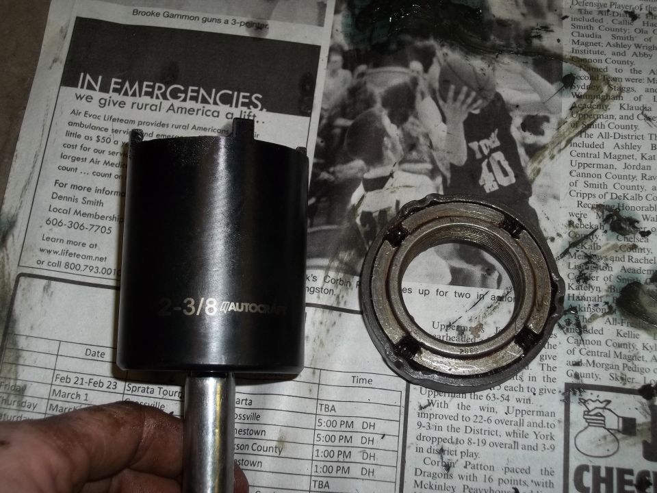 Black socket wrench part and bearing on newspaper