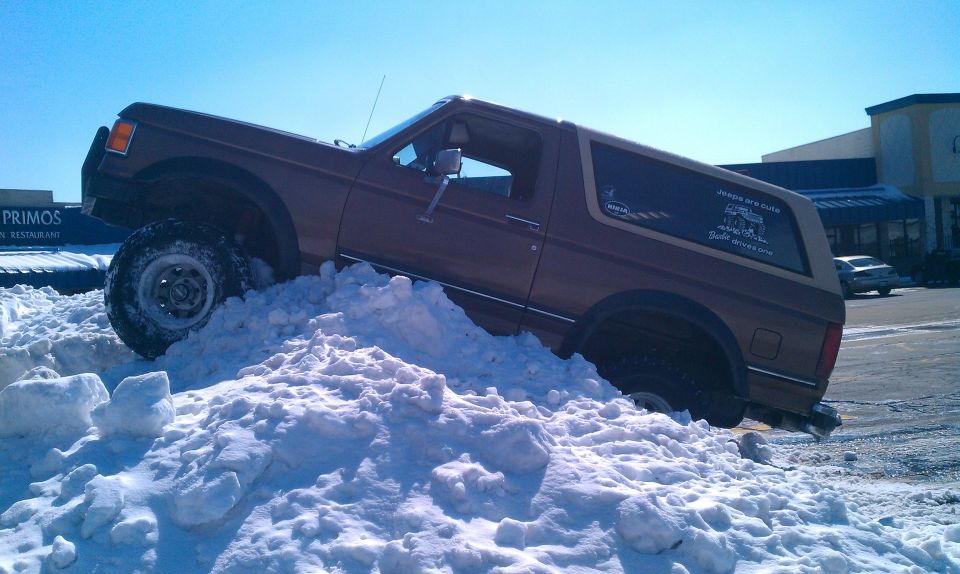 Brown 1987 Ford Bronco climbing a snow pile