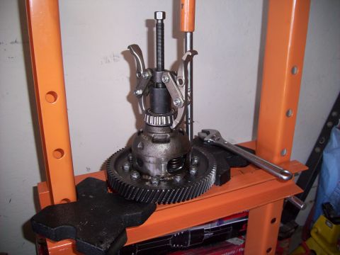 1995 Ford Probe - A differential gear assembly is shown with a puller tool attached, resting on a press with a wrench nearby.