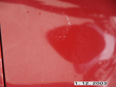 1998 Mercury Sable - Close-up of a red car panel showing smudges and imperfections.
