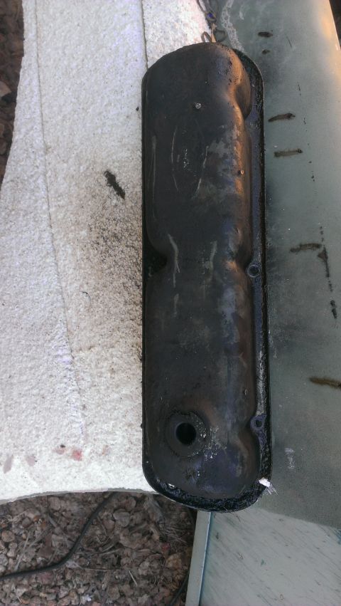 1990 Ford Bronco - A black valve cover, likely from an engine, is shown in detail against a textured background.