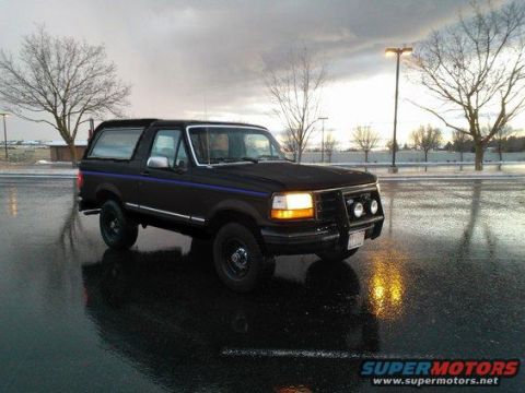 1992 Ford Bronco - Black 1992 Ford Bronco with blue side stripe parked outside on a cloudy day.