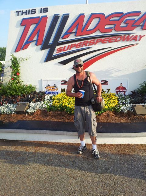 1986 Ford Bronco - Man poses for a photo in front of the iconic Talladega Superspeedway entrance sign.