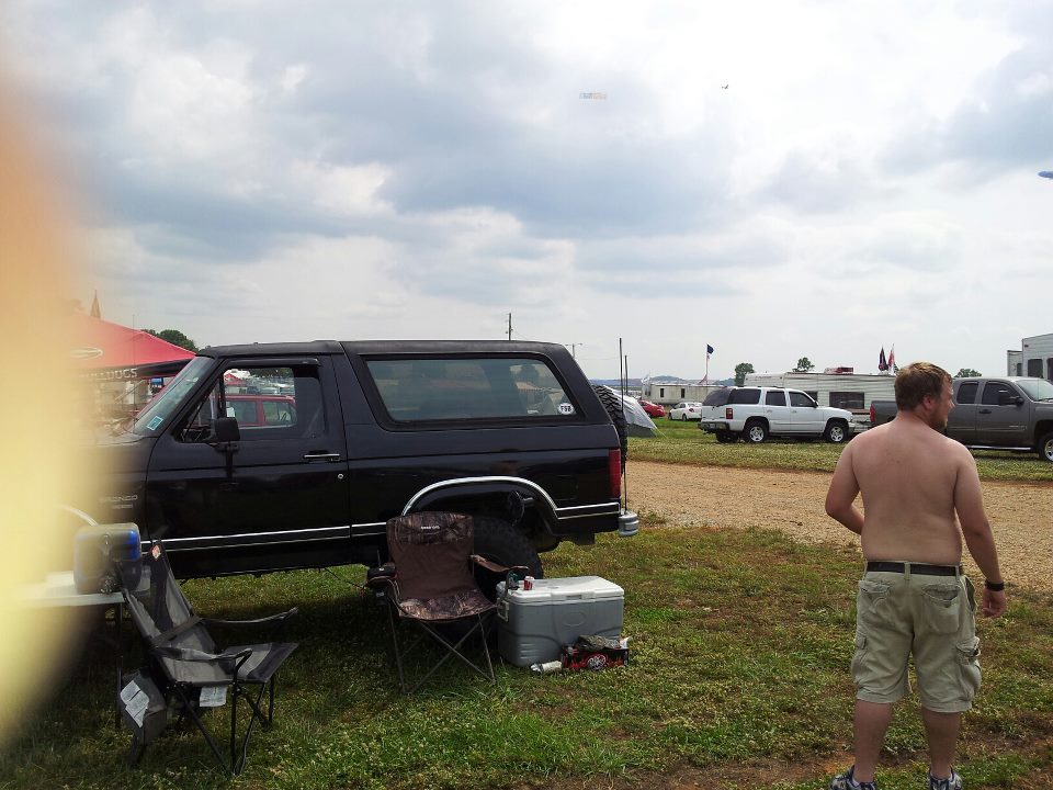 Black Ford Bronco parked on grass with a man standing nearby.