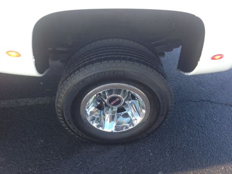2008 GMC Sierra 3500 - Close-up of the rear dual wheels on a white GMC truck, showing the chrome hubcap and tire details.