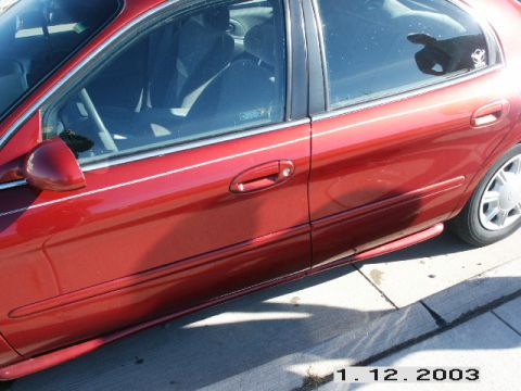 1998 Mercury Sable - The side profile of a red sedan is visible, showing the door handles and part of the rear wheel.
