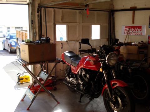 2008 Ford Crown Victoria - A red Suzuki motorcycle is parked in a garage, with a blue car visible outside.