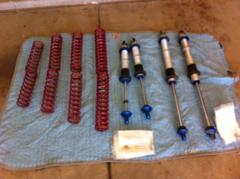 1987 Suzuki Samurai - A collection of red suspension springs and silver shock absorbers with blue accents are displayed on a quilted mat, likely for a vehicle re…
