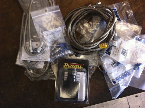 1987 Suzuki Samurai - A collection of braided stainless steel brake lines and assorted fittings are laid out on a surface.